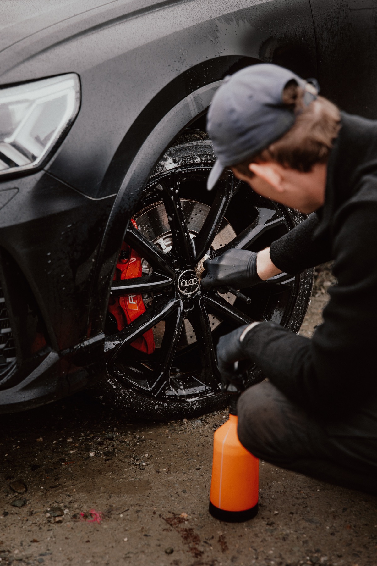 Mason applying pre-wash foam to Audi RS wheel with red brake calipers